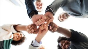 Cinco pessoas unem as mãos com os punhos cerrados