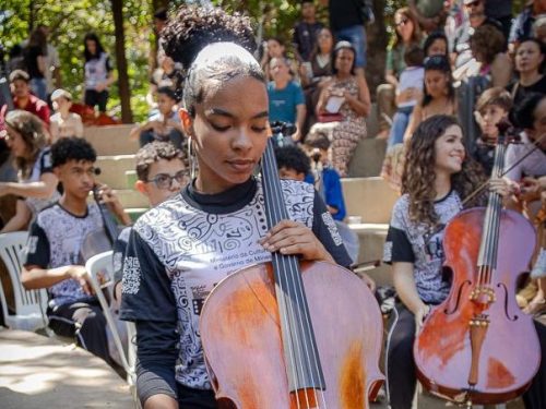 menina tocando violoncelo junto com orquestra social